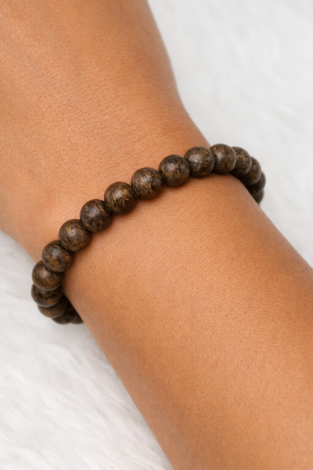 Bronzite bead stretch bracelet on wrist, dark bronze-brown round beads