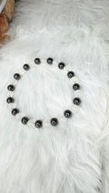 Stretch beaded bracelet with dark hematite and white moonstone beads, laid flat