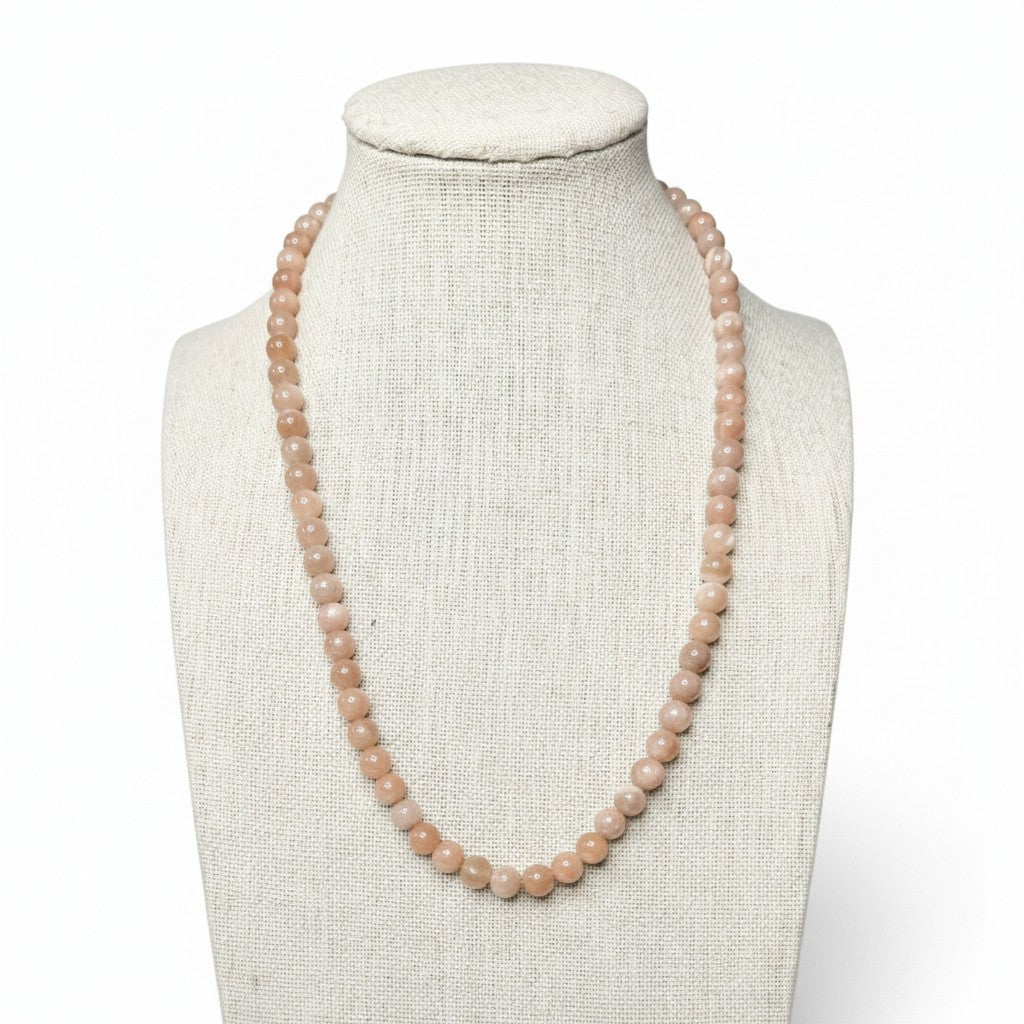 Peach-toned gemstone beaded stretch necklace on a mannequin, round beads