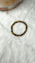 Tiger eye bracelet with round amber and dark beads on white fur