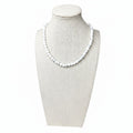 Matte white howlite beaded stretch necklace on display bust, small round beads