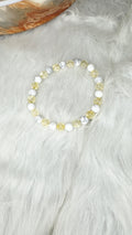 Round-stone beaded stretch bracelet with white and golden beads, viewed from above